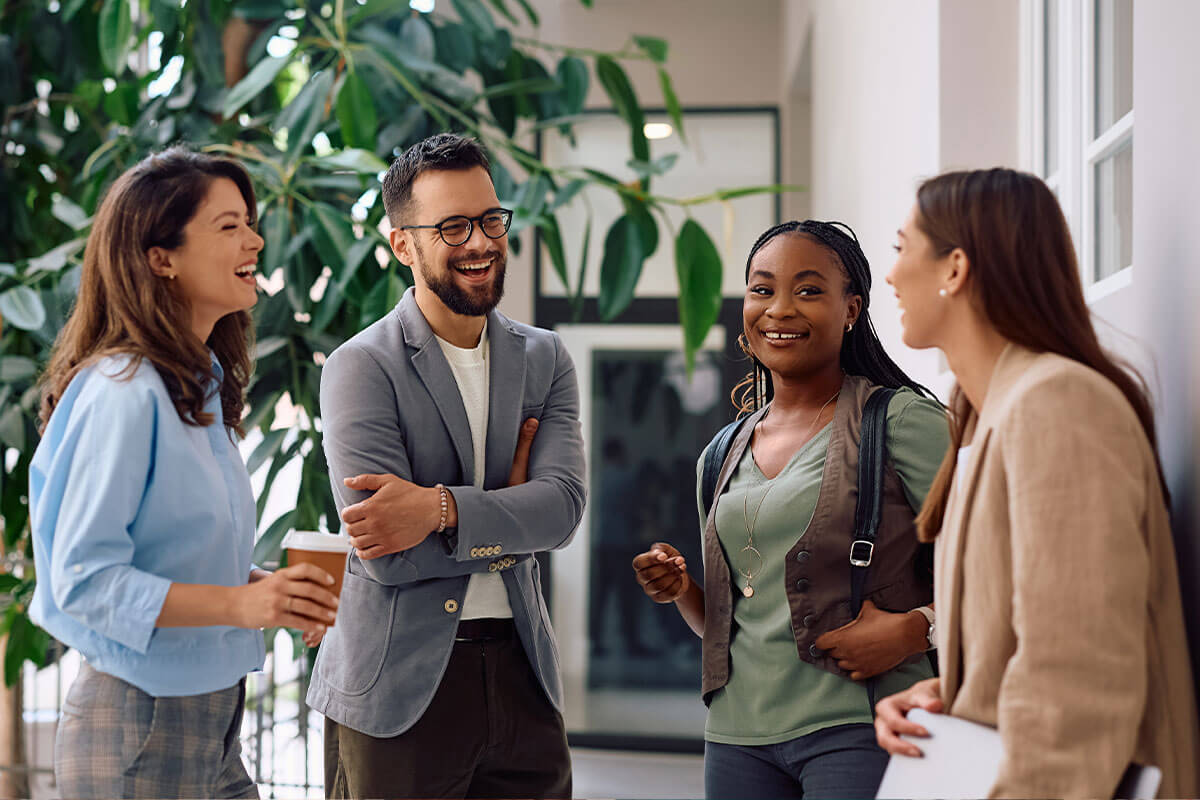A diverse group of business professionals smiling and discussing ideas in a collaborative environment.