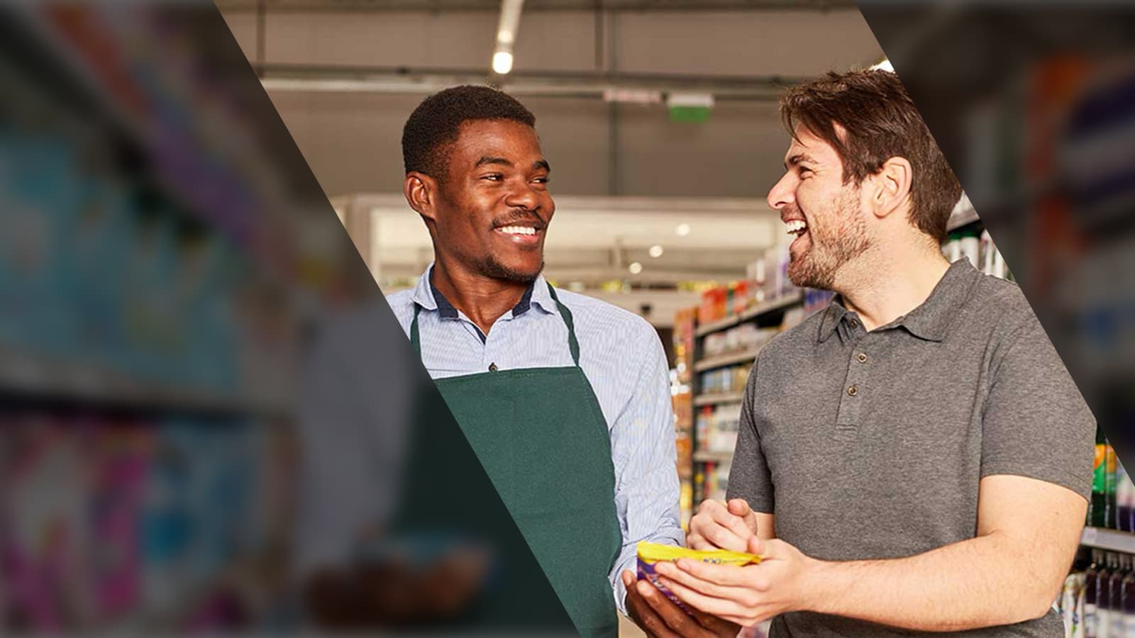 Two men in a supermarket aisle laughing together.